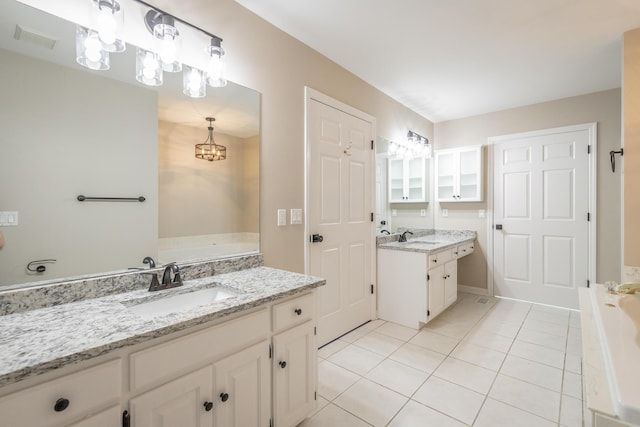 bathroom featuring two vanities, a sink, a garden tub, and tile patterned floors