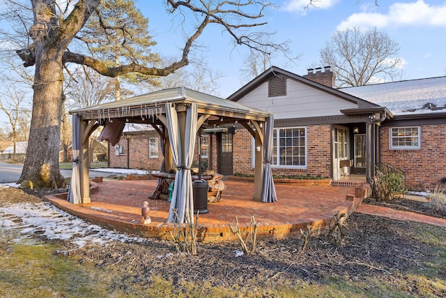 exterior space with a gazebo, brick siding, a chimney, and a patio area