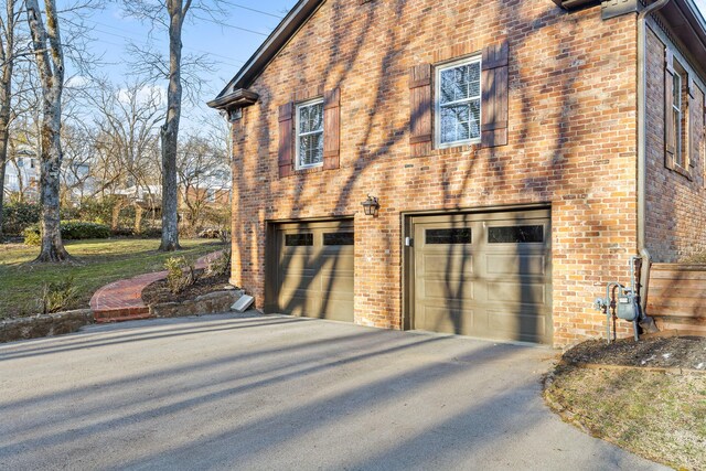 view of property exterior with a garage, driveway, and brick siding