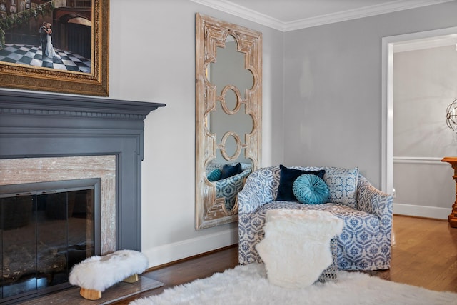 sitting room featuring ornamental molding, a glass covered fireplace, baseboards, and wood finished floors