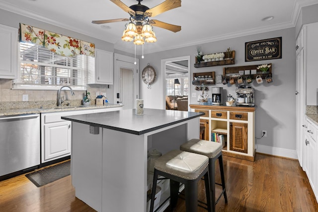 kitchen featuring decorative backsplash, dishwasher, a breakfast bar area, dark wood-type flooring, and a sink