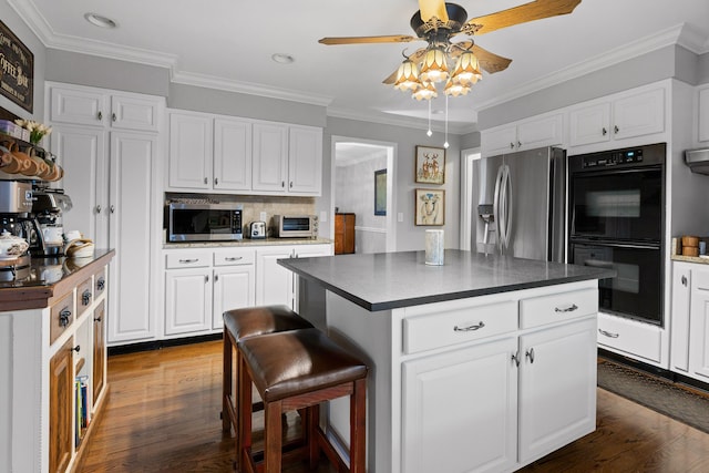 kitchen featuring appliances with stainless steel finishes, dark countertops, and dark wood-style floors