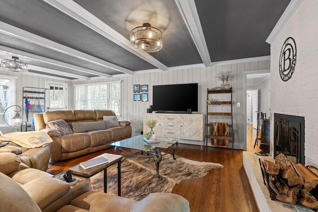 living area with ornamental molding, a brick fireplace, wood finished floors, and beam ceiling