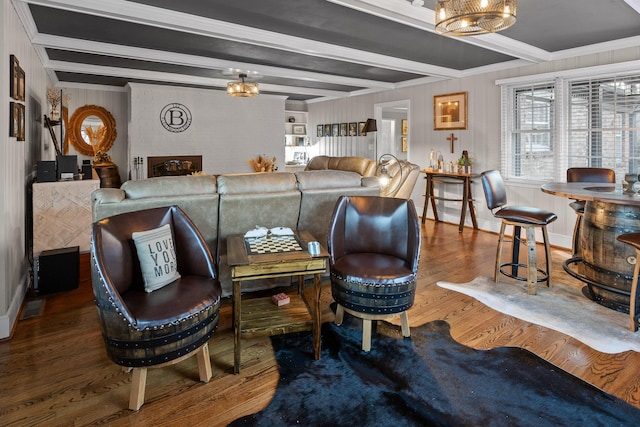 living area featuring beamed ceiling, wood finished floors, and an inviting chandelier