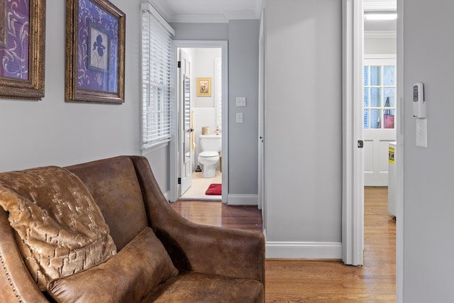 living area with ornamental molding, baseboards, and wood finished floors