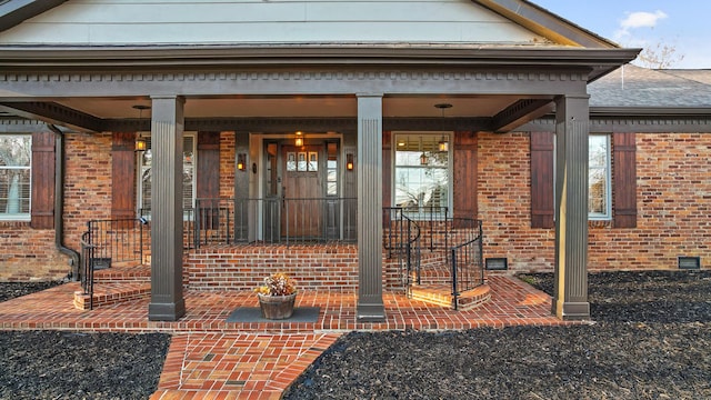 entrance to property with covered porch, brick siding, and crawl space