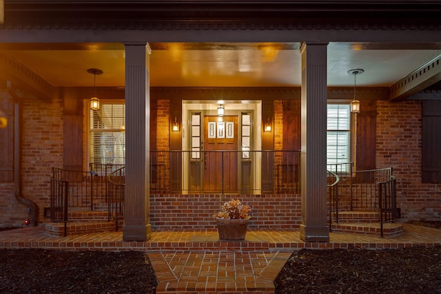 property entrance with covered porch and brick siding