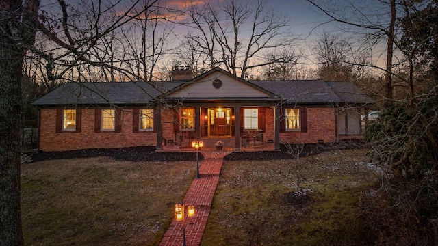 view of front facade featuring a porch, crawl space, brick siding, and a chimney