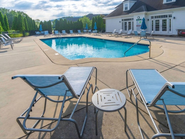 pool featuring french doors, a patio area, and a mountain view