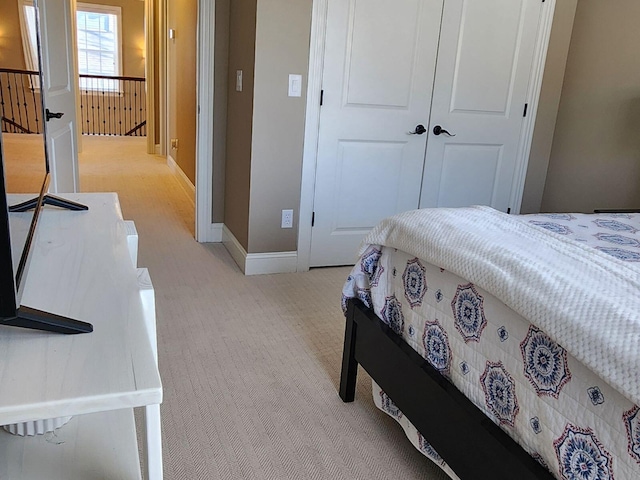 bedroom with baseboards, a closet, and light colored carpet