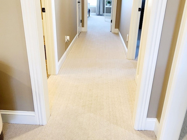 hallway featuring baseboards and light colored carpet