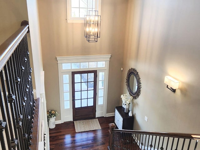 foyer featuring baseboards, dark wood finished floors, stairway, a high ceiling, and a notable chandelier