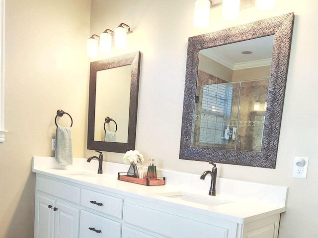 full bathroom with double vanity, a stall shower, a sink, and crown molding