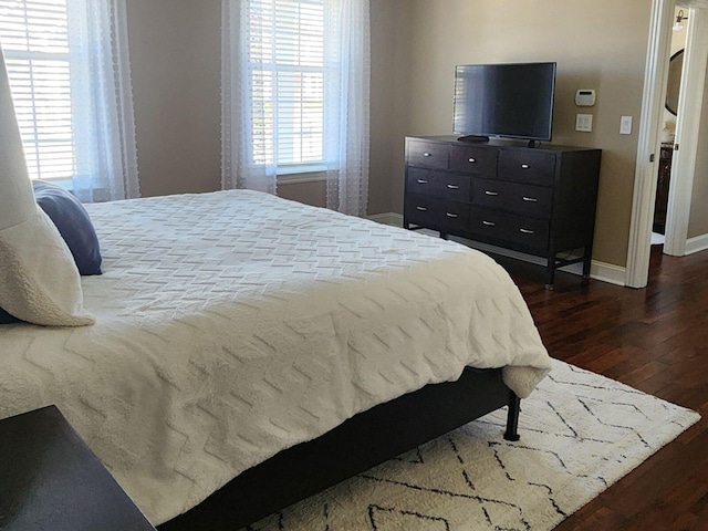 bedroom with dark wood finished floors and baseboards