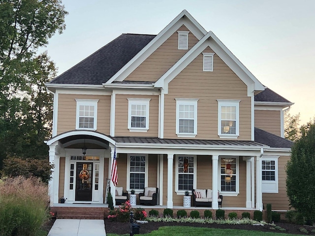 view of front of house with metal roof, a shingled roof, a porch, and a standing seam roof