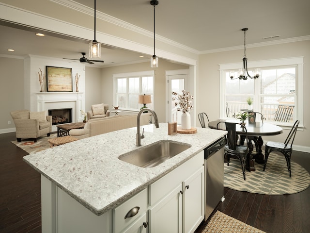 kitchen with light stone counters, a kitchen island with sink, a sink, white cabinets, and stainless steel dishwasher