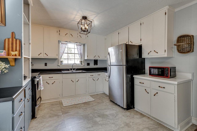 kitchen with stainless steel appliances, dark countertops, white cabinets, and a sink