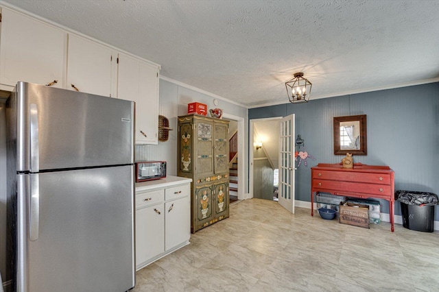 kitchen with crown molding, light countertops, freestanding refrigerator, white cabinetry, and a textured ceiling