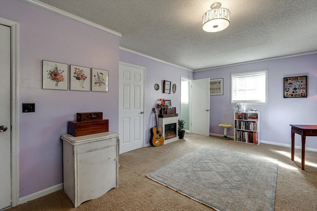 interior space featuring a textured ceiling, ornamental molding, a glass covered fireplace, and baseboards