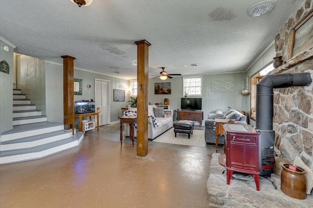 living area featuring a textured ceiling, finished concrete floors, stairway, a wood stove, and crown molding