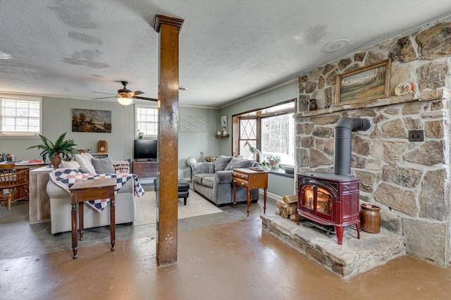 living area with concrete flooring, a wood stove, and a healthy amount of sunlight