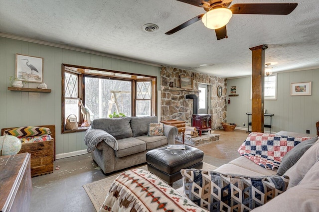 living room featuring concrete flooring, a textured ceiling, and a wood stove