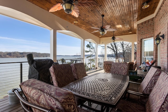 deck with ceiling fan, outdoor dining area, and a water view