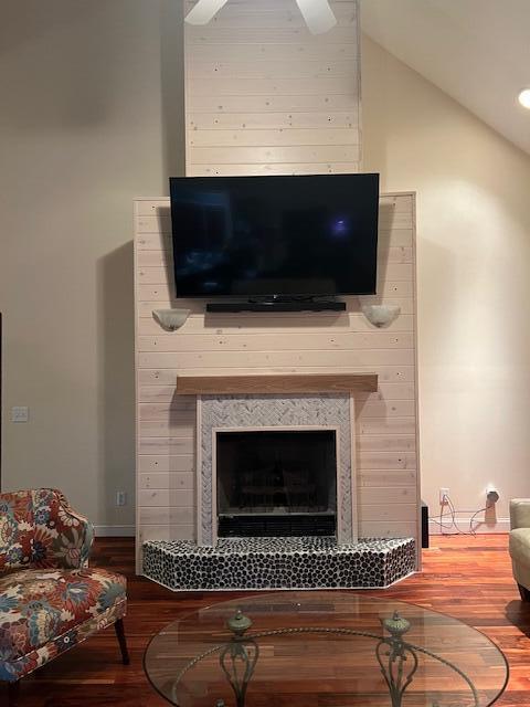 interior details with a fireplace, a ceiling fan, and wood finished floors