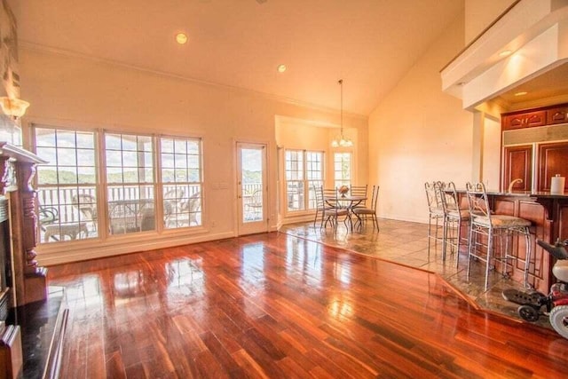 interior space featuring an inviting chandelier, baseboards, high vaulted ceiling, and wood finished floors