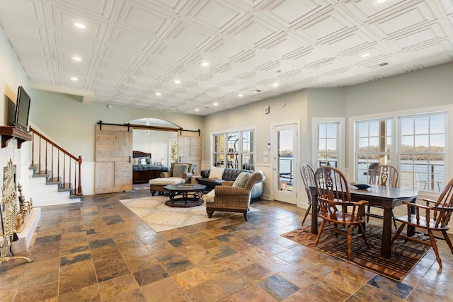 living area with a barn door, visible vents, baseboards, a water view, and recessed lighting