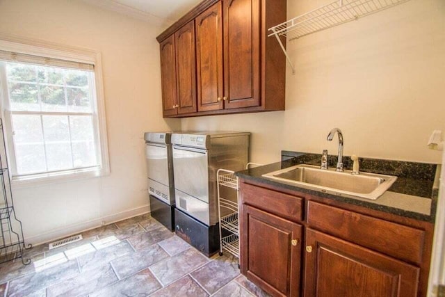 laundry room featuring cabinet space, visible vents, washing machine and dryer, a sink, and baseboards