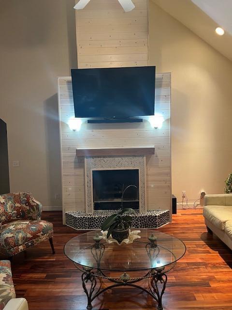 living room featuring high vaulted ceiling, recessed lighting, a fireplace, wood finished floors, and baseboards