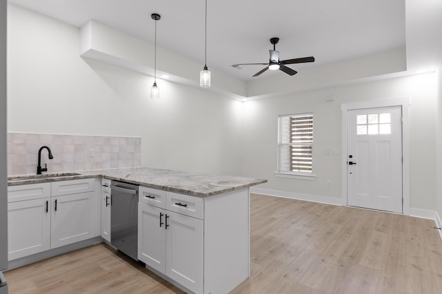 kitchen featuring light stone counters, a sink, white cabinetry, stainless steel dishwasher, and decorative light fixtures