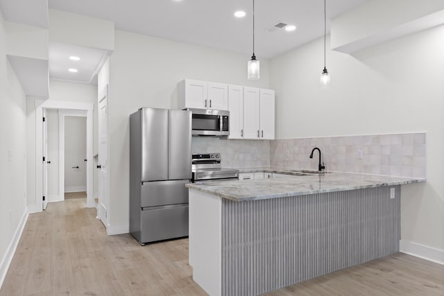 kitchen featuring stainless steel appliances, white cabinets, a sink, and a peninsula