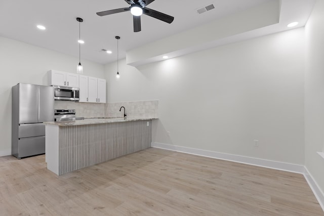 kitchen featuring visible vents, light stone counters, a peninsula, stainless steel appliances, and white cabinetry