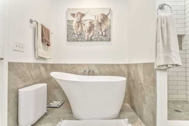 full bathroom featuring a freestanding tub, tile walls, a wainscoted wall, and tiled shower