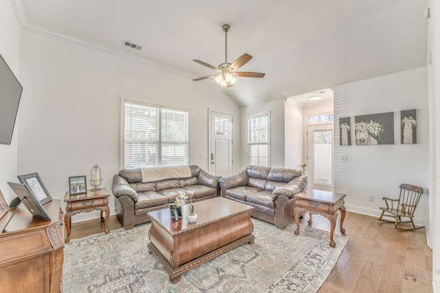 living area featuring visible vents, baseboards, vaulted ceiling, ornamental molding, and light wood-type flooring