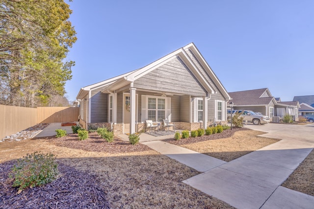 view of front of home with stone siding, fence, and a porch