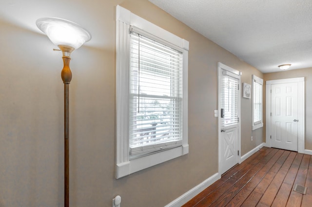 entrance foyer with dark wood-style floors, a textured ceiling, visible vents, and baseboards