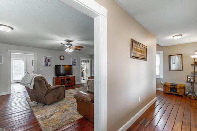 living area with dark wood-style floors, visible vents, a textured ceiling, and baseboards