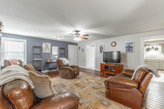 living room with light wood-style floors, baseboards, and a textured ceiling