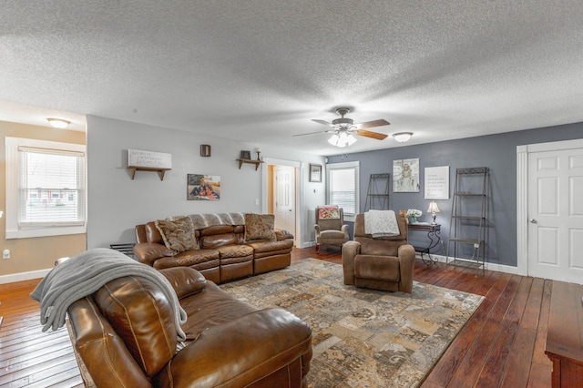 living room with baseboards, dark wood-type flooring, a ceiling fan, and a healthy amount of sunlight