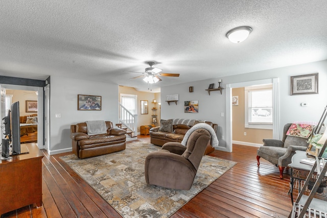 living room featuring dark wood-style floors, baseboards, stairway, and a ceiling fan