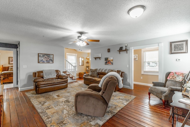 living area featuring ceiling fan, a textured ceiling, baseboards, and wood finished floors