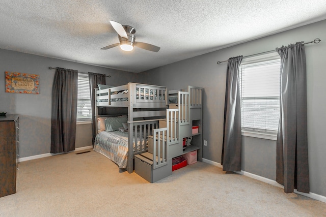 bedroom featuring light colored carpet, ceiling fan, a textured ceiling, and baseboards