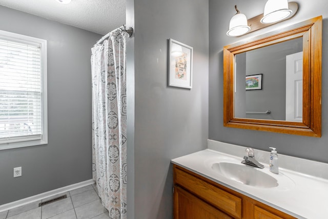 bathroom featuring baseboards, visible vents, tile patterned flooring, a textured ceiling, and vanity