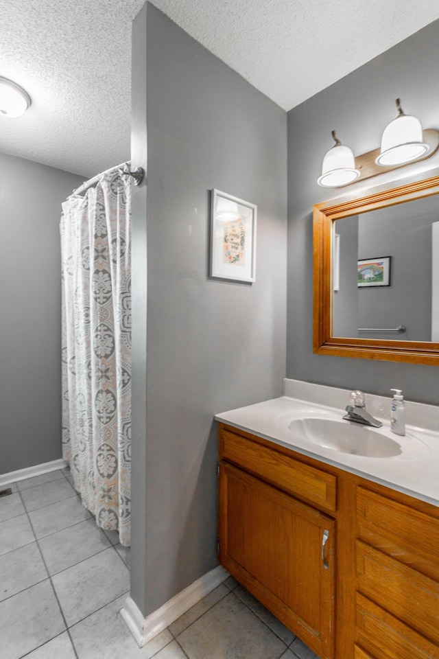 bathroom with vanity, baseboards, a textured ceiling, and tile patterned floors