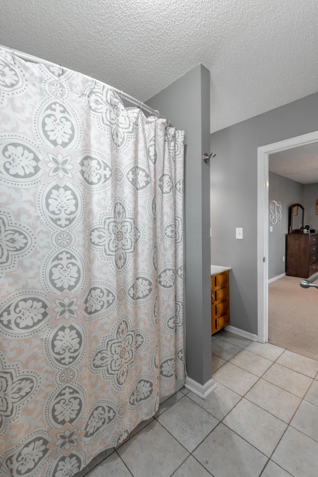 full bathroom with baseboards, a textured ceiling, and tile patterned floors