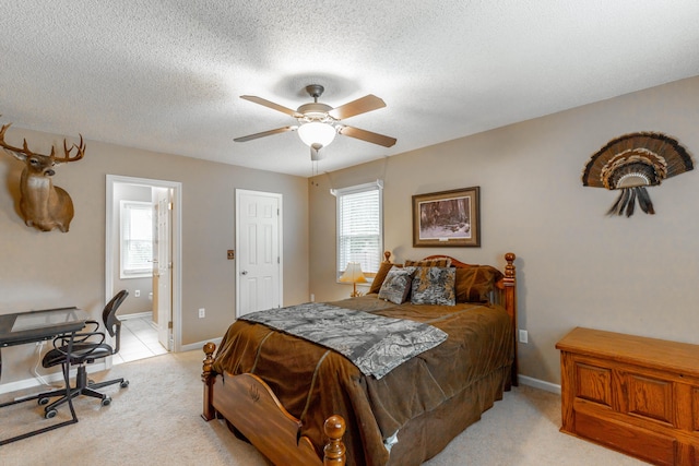 bedroom with light carpet, ensuite bath, baseboards, and a textured ceiling