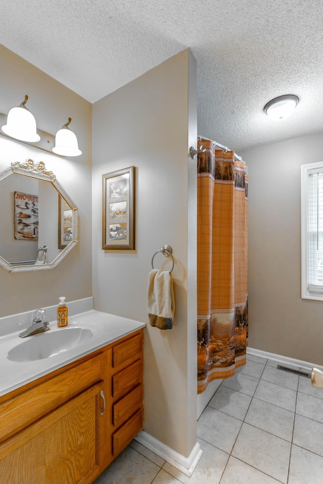 full bath with baseboards, visible vents, tile patterned floors, a textured ceiling, and vanity